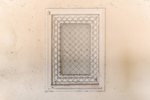 Old window with bars on the wall of a rural house