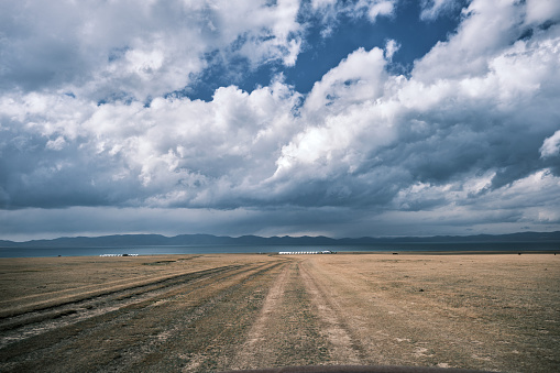 View of yurt camp on highland lakeshore under cloudy sky (Song-Kul lake, Naryn region, Kyrgyzstan)