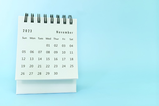 Selective focus of November 2023 desk calendar on blue background with copy space.