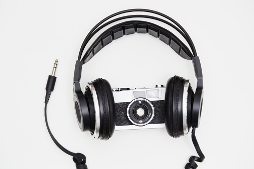 Music and photography. SLR film camera and music headphones on white background