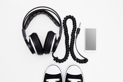 Smart phone mockup with headphones and sneakers on white background
