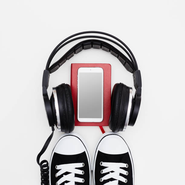 Headphone, smart phone, red book and sneakers on white background