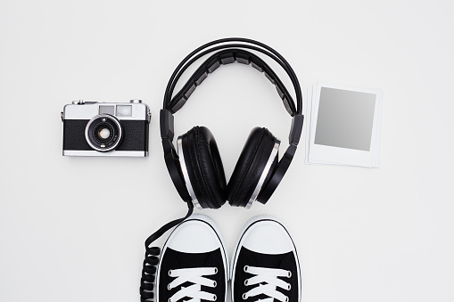 Headphones, film camera, instant print frames and sneakers on white background