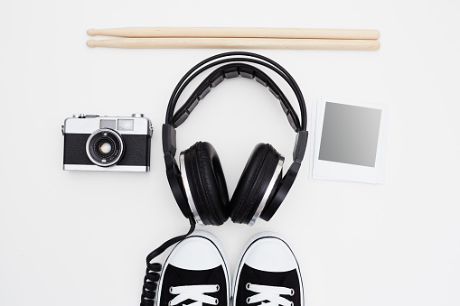 Headphones, drumsticks, film camera, instant print frames and sneakers on white background