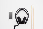 Wired headphones, smart phone, coffee mug and wooden drumsticks on white background