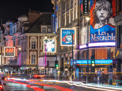 Traffic zooming along Shaftesbury Avenue past the tourist crowds and the billboards of London’s vibrant theatre district at night.