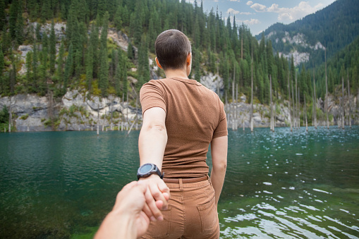 Follow me. A woman brought her man on a date in nature. Spend time on the mountain lake Kaindy in Qazaqstan.