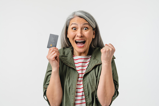 Impressed shocked pleased middle-aged mature woman bank client customer grandmother holding credit card discount sale card for buying clothes, loan, cashback, debt, mortgage
