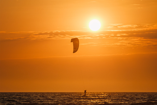 Athletic man having fun while kitesurfing on the sea. Copy space.