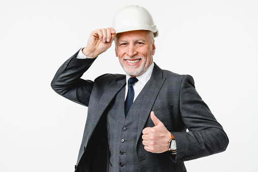 Happy caucasian mature middle-aged construction worker architect engineer wearing suit and hardhat showing thumb up isolated in white background