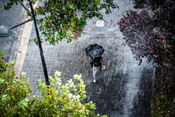 Aerial view of a man with umbrella walking under heavy rain stock photo