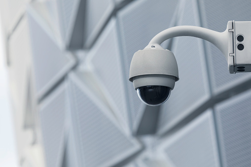 A security camera on an office building wall in the city.