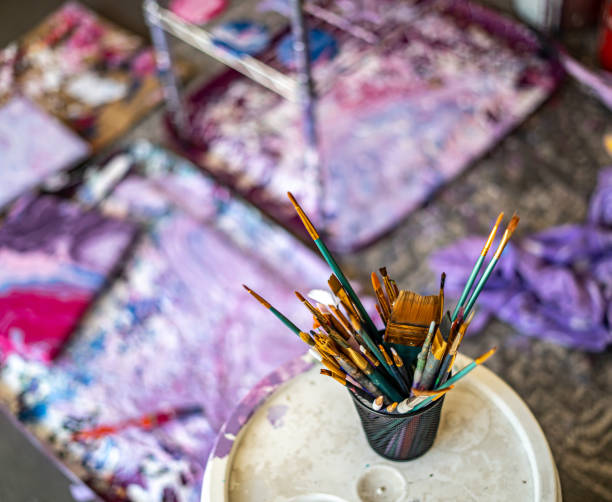 istock Cup of Paintbrushes with Purple Abstract Art in Background Studio 1654738082