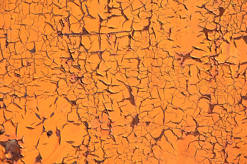 A wall with rust and orange paint in bad condition.