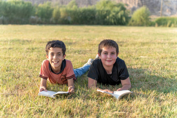 Boys reading books in nature.