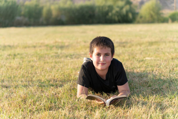 istock Boy reading books in nature. 1654795316