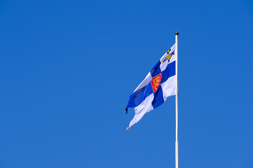 Helsinki / Finland - JUNE 27, 2023: Finnish state flag waiving in the wind against a bright blue sky.