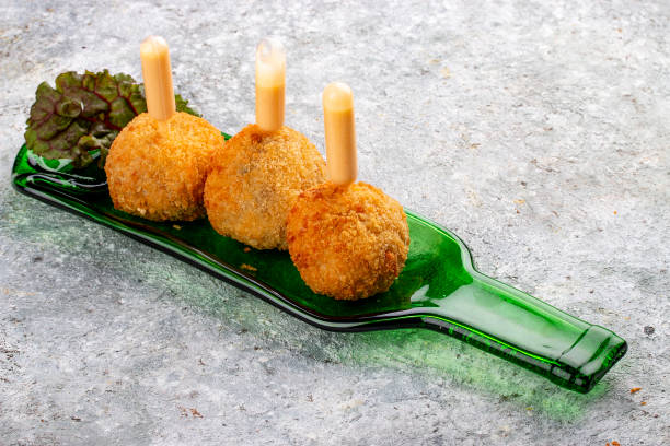 istock Cheese balls deep-fried with white sauce on a decorative plate. Isolated image on a gray background. 1654799120