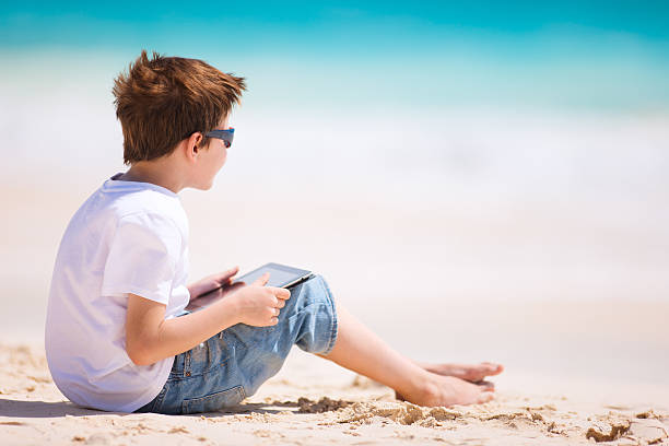 мальчик с планшет на пляже - child beach digital tablet outdoors стоковые фото и изображения