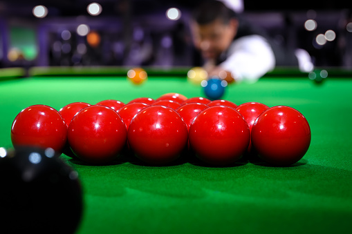 Snooker red ball group set with snooker player blur in background while aiming red ball on snooker table.