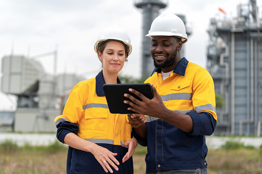 Highly skilled engineers is depicted diligently at work, using digital tablet, collaboratively advancing the industry through collective expertise. Serves as a powerful tool for Innovation and Intelligence. Power of Data Analysis, Efficiency, and Risk Management ensure the safety and sustainability operations.
