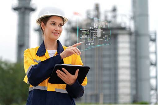 Production engineer of industrial innovation with digital tablet. Standing at electric power plant and looking at plant layout factory on the graphic screen with high technology. Intelligence drive efficiency and continuous improvement.