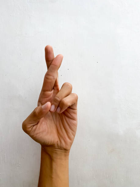 istock Hand showing two crossed fingers over isolated white background gesturing lying expression doing lie symbol with fingers. Concept for trust issue, no truth, fake, cheat, liar, tricky, false information, imposter. 1654892927
