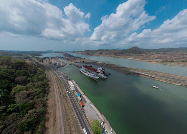 Boat passing Pedro Miguel locks in Panama, famous channel shortcut in central America. Visible ships and channels with locks. Drone view on a cloudy but sunny day in spring. Boat passing Pedro Miguel locks in Panama, famous channel shortcut in central America. Visible ships and channels with locks. Drone view on a cloudy but sunny day in spring. panama canal expansion stock pictures, royalty-free photos & images