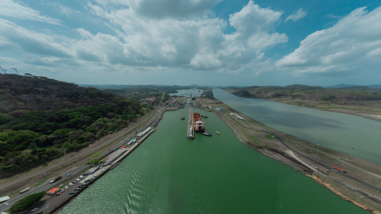 Boat passing Pedro Miguel locks in Panama, famous channel shortcut in central America. Visible ships and channels with locks. Drone view on a cloudy but sunny day in spring.
