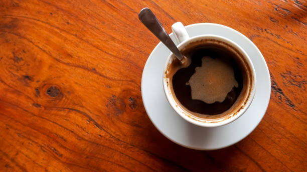 istock Hot black coffee in a white cup placed on a brown wooden table. It is usually served for breakfast or during breaks. Concept for working, task, job, business plan, and outdoor cafe. 1654899589
