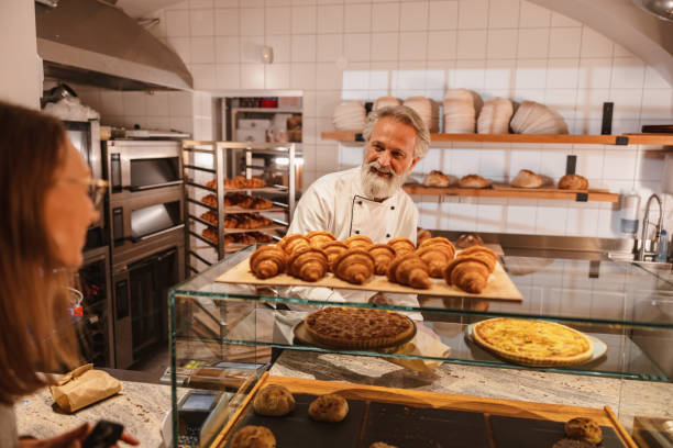 istock Friendly Baker Attending A Young Costumer At The Bakery 1654901430