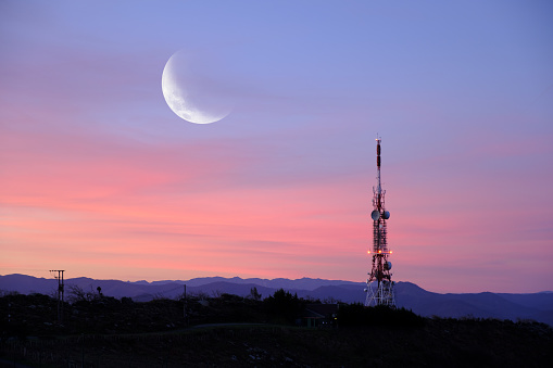Wireless technology. Communication tower with the moon at dawn.