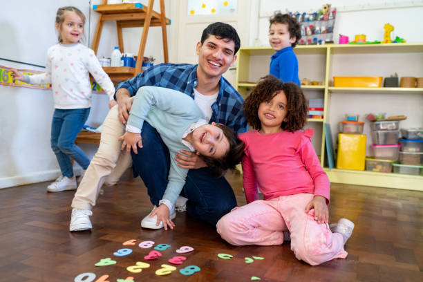 portrait of diverse group of kids and cheerful teacher learning numbers and smiling very playfully at the camera - preschooler child playing latin american and hispanic ethnicity imagens e fotografias de stock