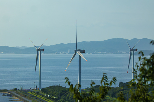A wind turbine standing by the sea and receiving sea breeze