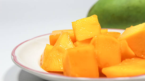 istock Fresh orange colored mangoes ready to eat placed on a white plate. Isolated on white background. Dice or cube shaped sliced mango fruit for dessert or appetizers. 1654912315