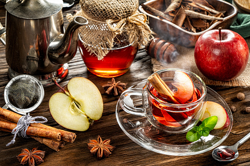 Food theme series: High angle close-up view of hot apple tea with cinnamon sticks infusion in a cup on a rustic table