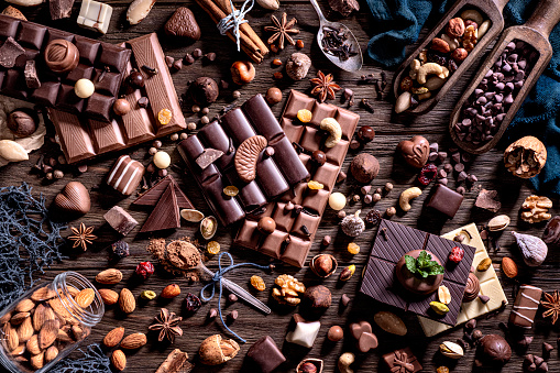 Food theme series: Table top view of a large assortment of chocolate, nuts and dried fruit on a rustic table