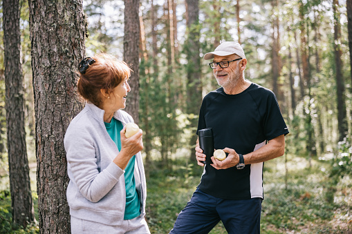 Husband and wife pursuing different outdoor activities in the pine forest and having a healthy active retirement.