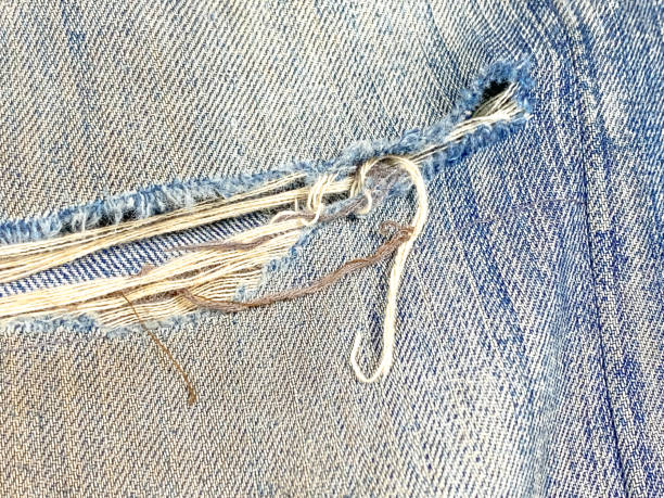 Destroyed torn denim blue jeans texture. Ripped denim blue cloth background. The dirty jeans with holes are torn and rotted so that the threads are visible