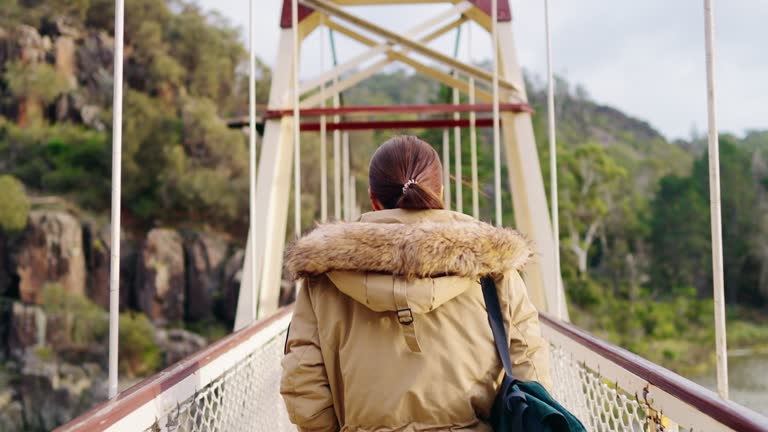 Woman walk hiking crossing a hanging bridge