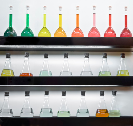 Colorful liquid in flasks laying on wall shelf