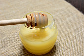 jar with honey and honey deeper isolated on burlap tablecloth close up