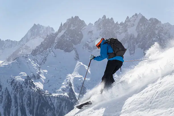 A skier making turns in the powder snow in Chamonic, France, The Mont Blanc Massif can be seen in the background.