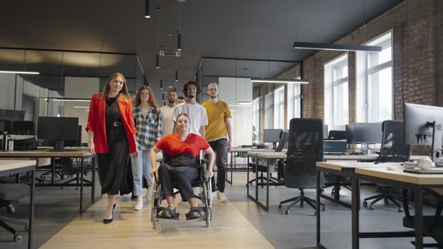 A modern young businesswoman in a wheelchair is surrounded by an inclusive workspace