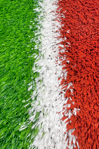 Close-up of a White Line Between Green and Red Plastic Grass on a Football Field Background