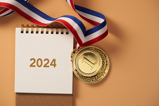 desk calendar year 2024 and gold medal  against orange background