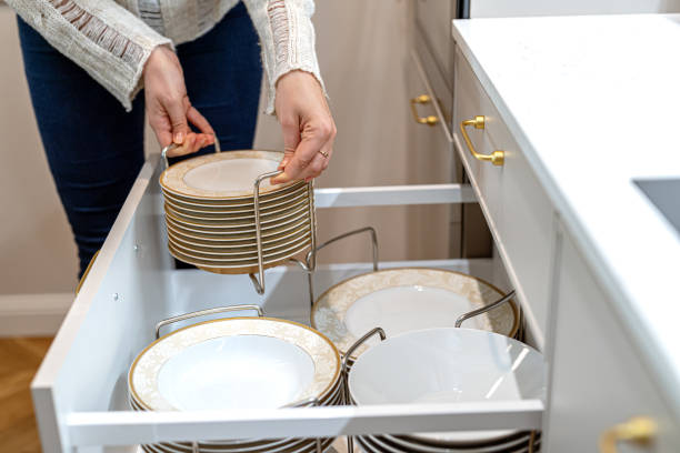 istock Woman placing porcelain plates into kitchen drawer. Storage organization system in kitchen cabinets. 1654999897