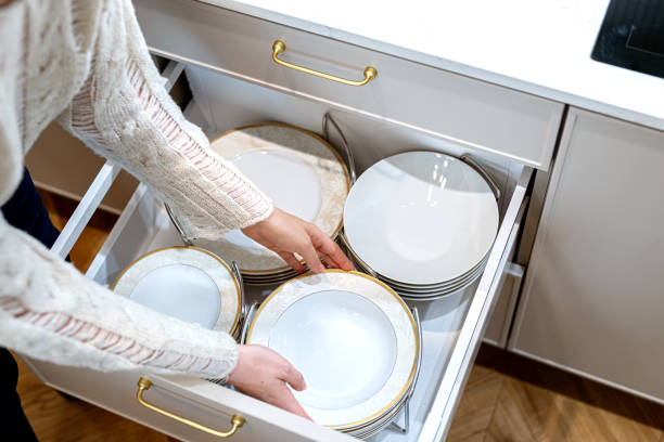 istock Woman placing clean porcelain plates into kitchen drawer. Storage organization system in kitchen 1654999904
