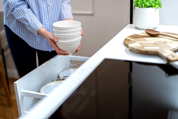 mulher organizando pratos de porcelana e tigelas na gaveta da cozinha. sistema de armazenamento em armários de cozinha - home interior women domestic kitchen cabinet - fotografias e filmes do acervo