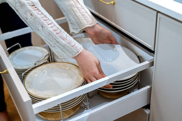 istock Woman placing porcelain plates into kitchen drawer. Storage organization system in kitchen 1655001976